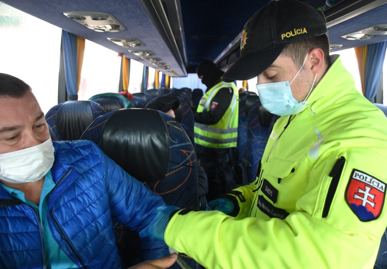 policajt kontroluje cestujúceho v autobuse
