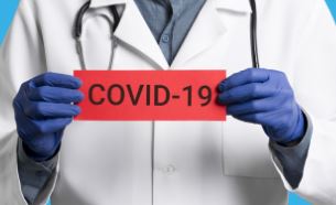 zdravotník držiaci červenú ceduľu s nápisom COVID-19